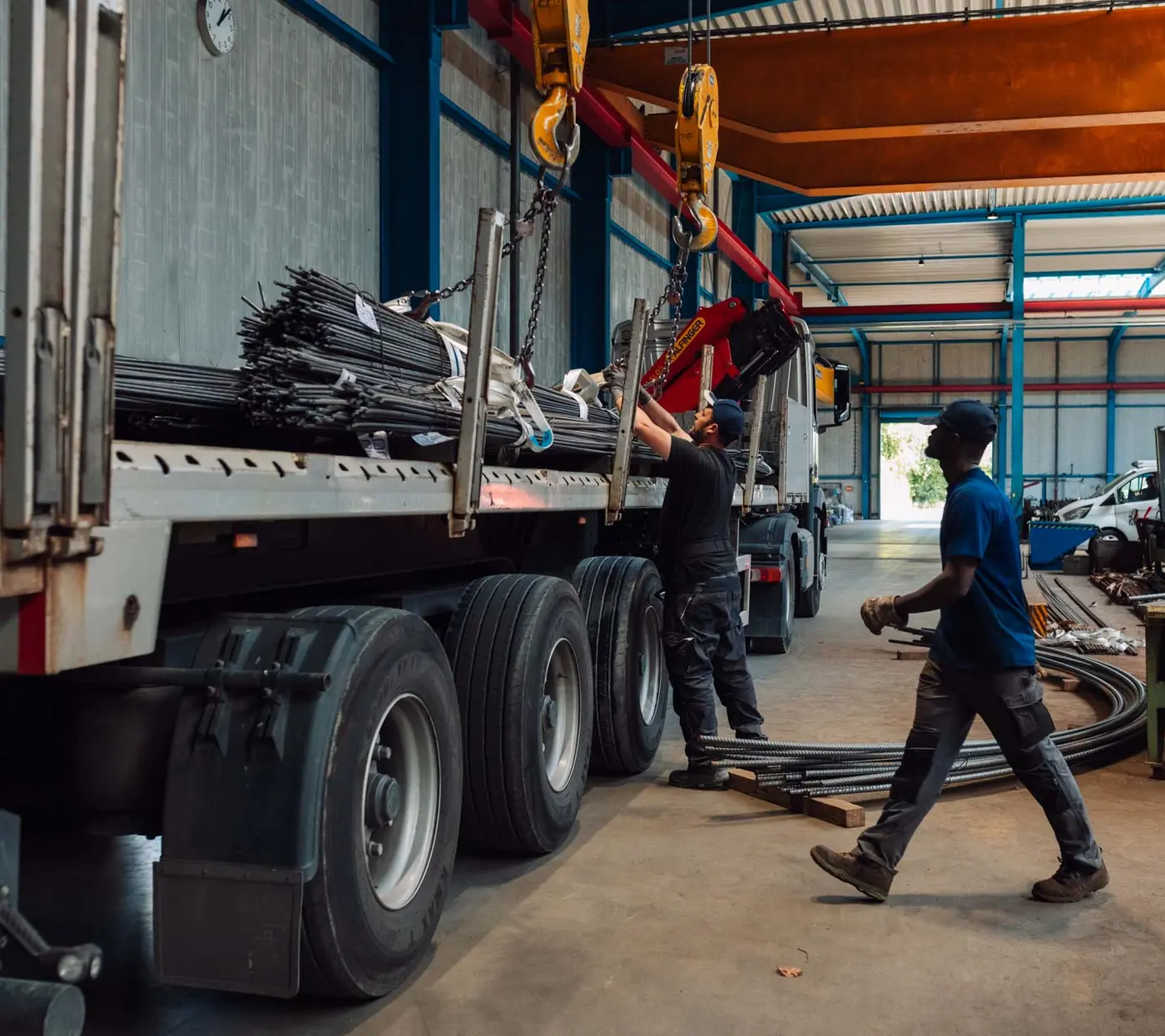 Lkw mit Ladekran wird in der Halle mit Betonstahl beladen