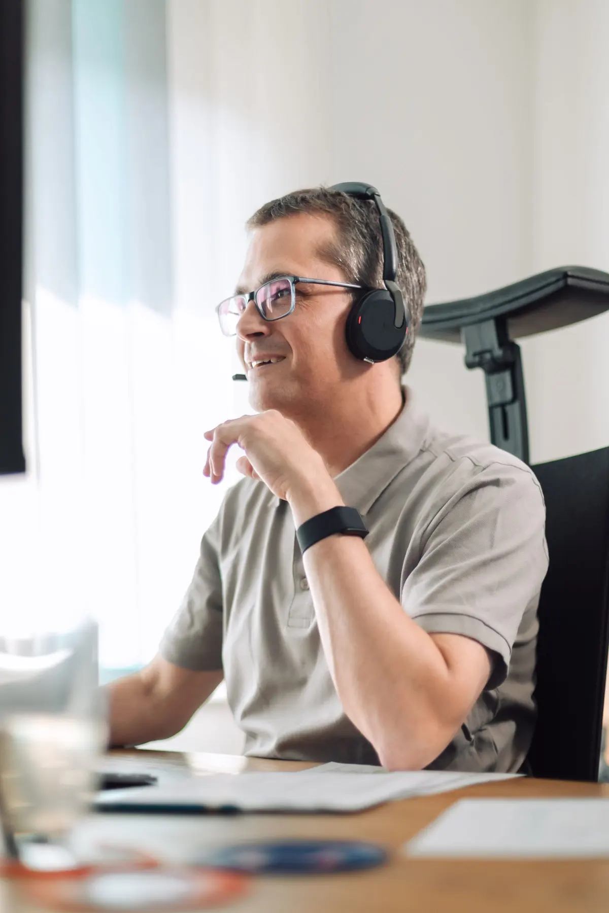 Mitarbeiter mit Headset führt am Schreibtisch ein Telefonat mit einem Interessenten