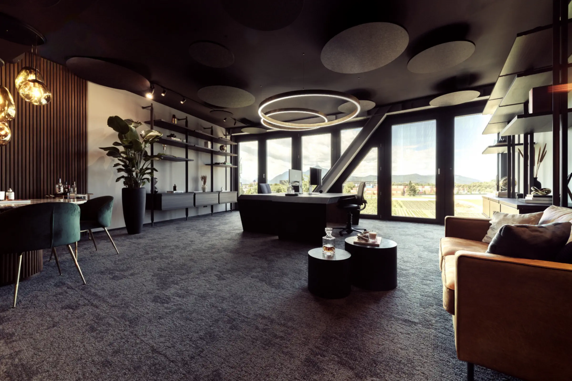 Lounge mit Ledersofa, Leuchtringen und bodentiefen Fenstern im Martin&Klein-Büro im Helix in Salzburg