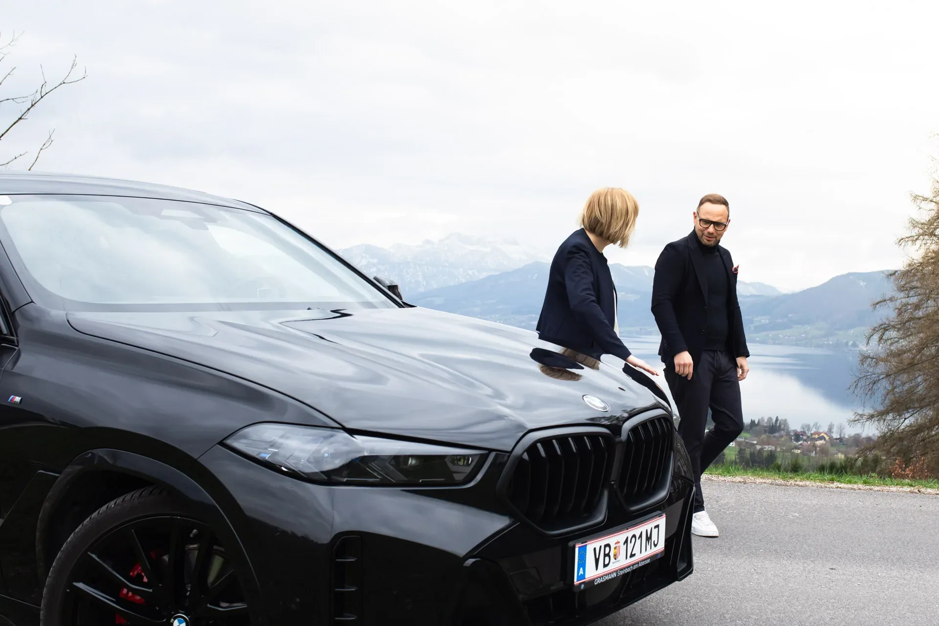 Zwei Personen neben einem BMW mit Blick auf den See