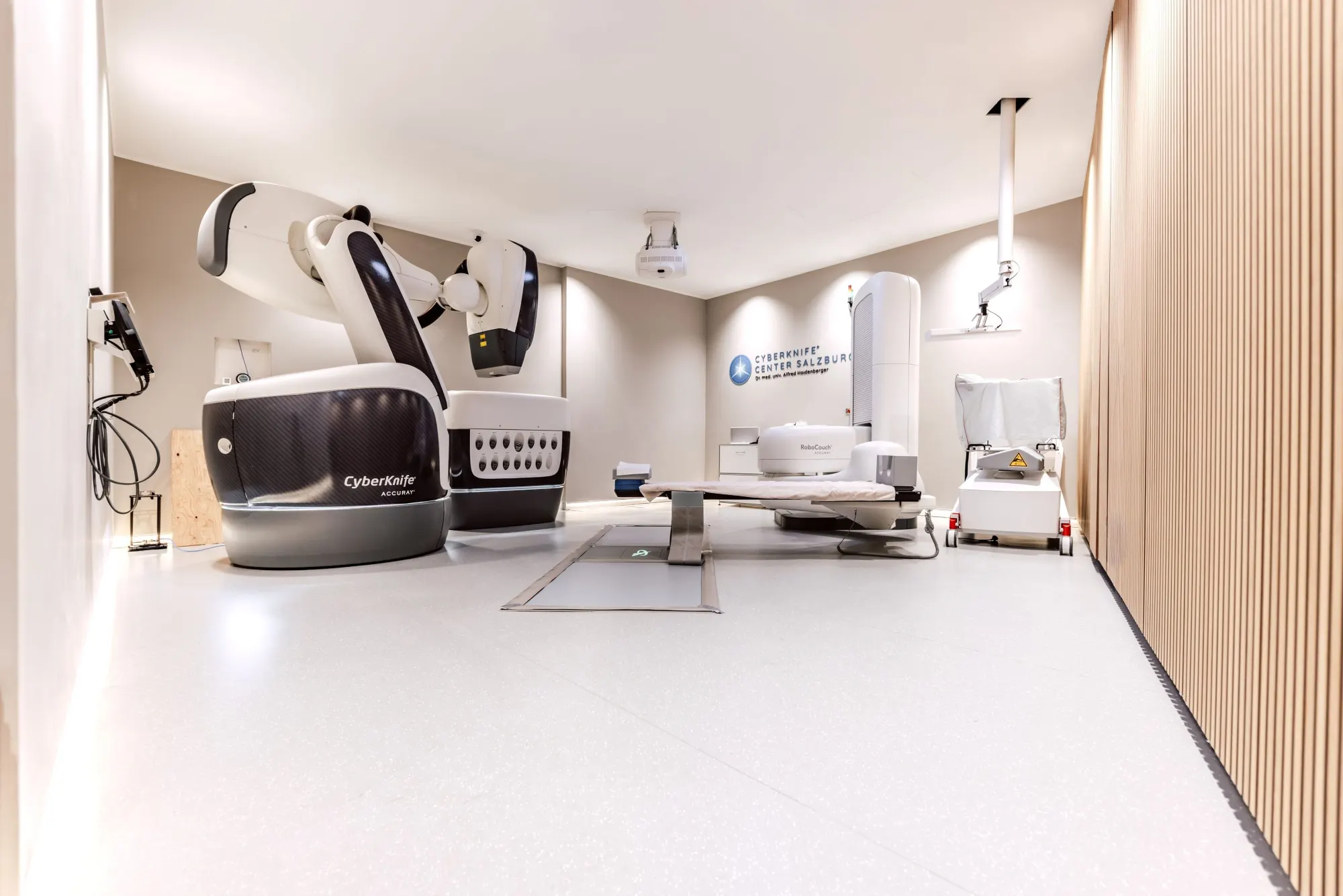 Behandlungsraum im CyberKnife Center Salzburg mit Roboterarm und Behandlungsliege