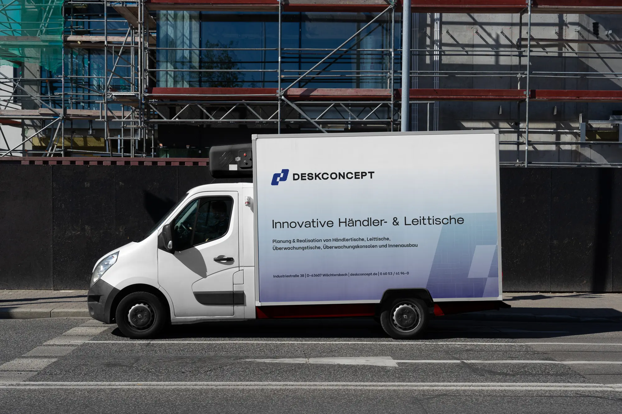 Transporter mit der Beschriftung von Desk Concept vor einer Baustelle