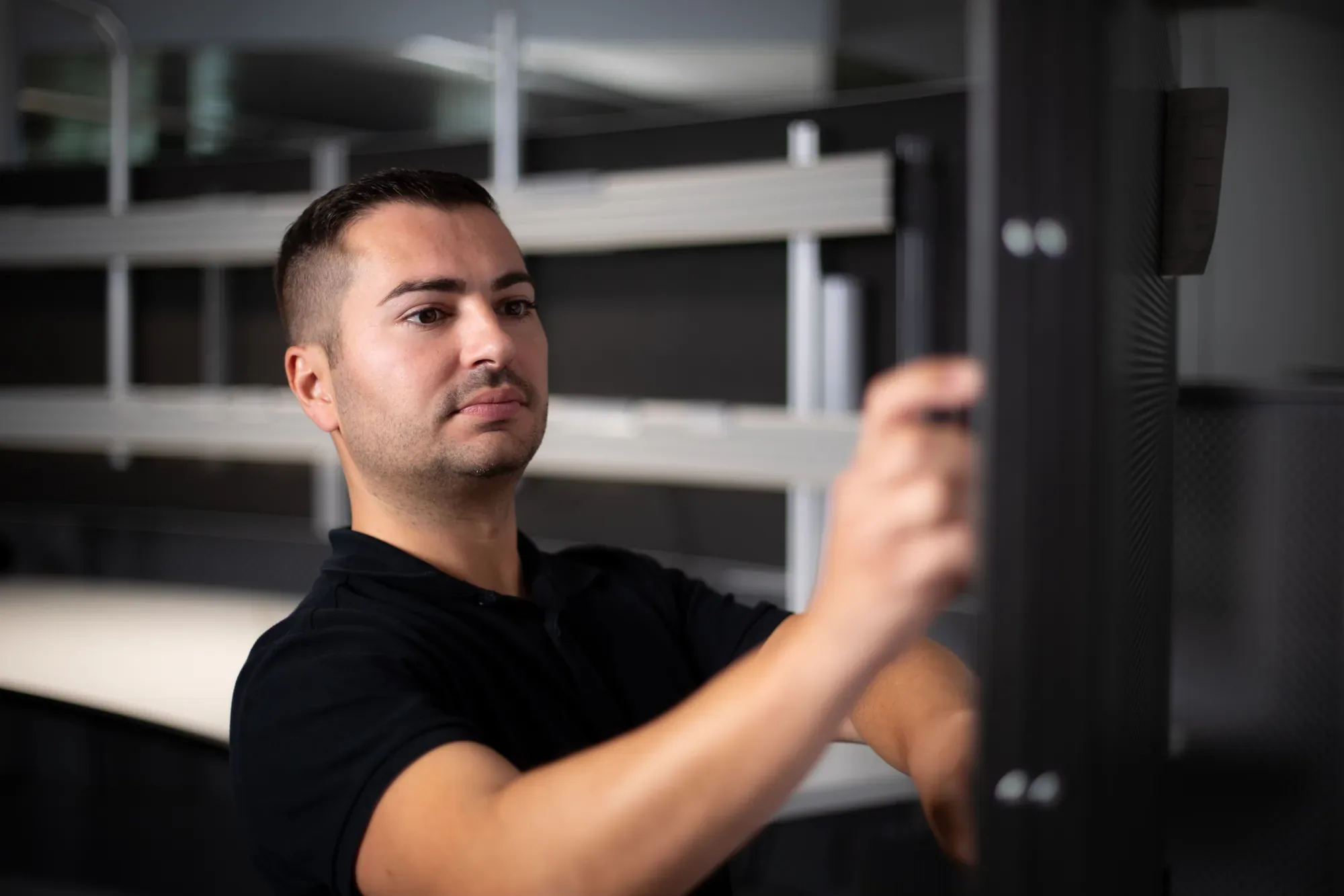 Marc Campanico richtet im dunklen Raum das Monitortragsystem eines Leittischs aus