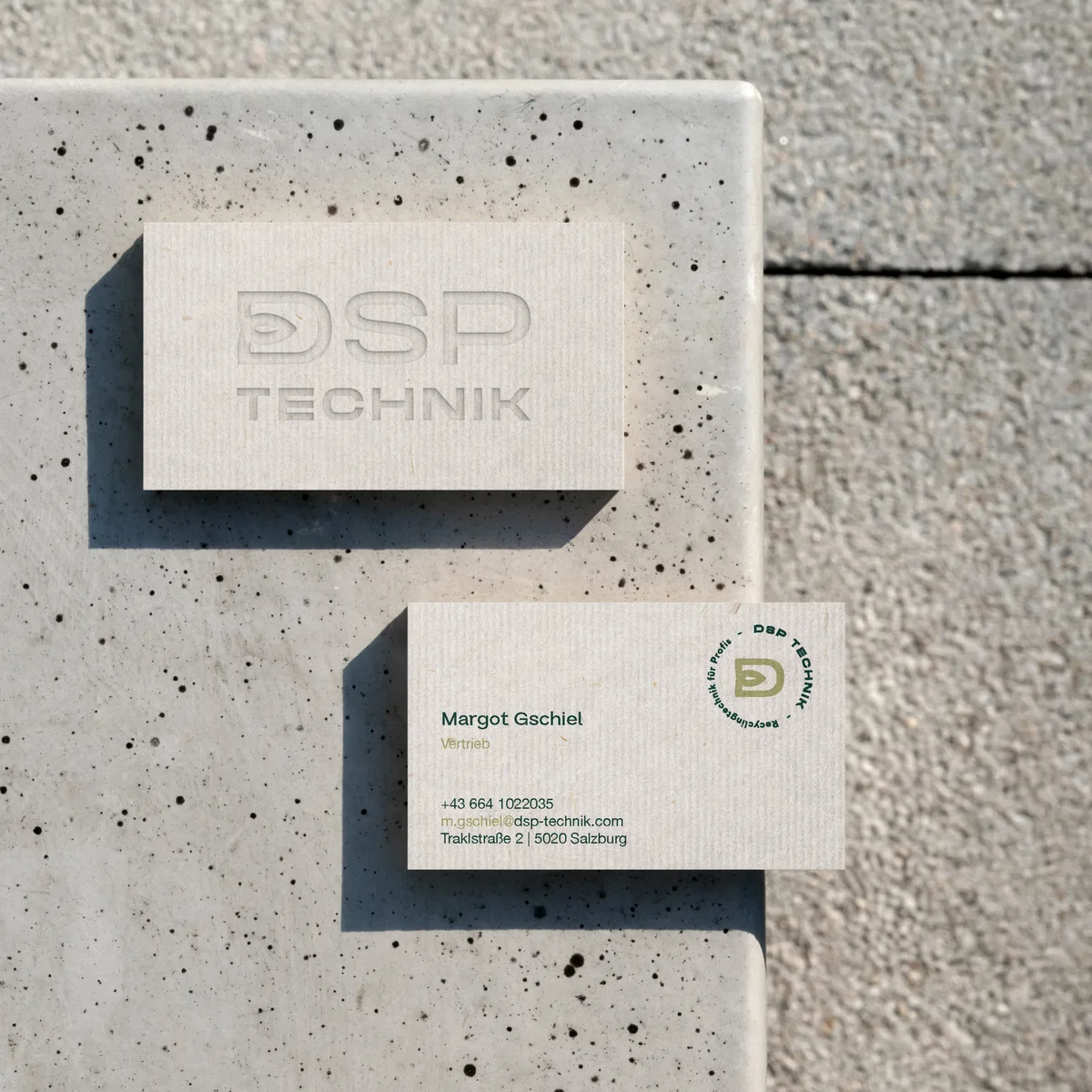 Visitenkarten von DSP Technik mit geprägtem Logo auf Sichtbeton