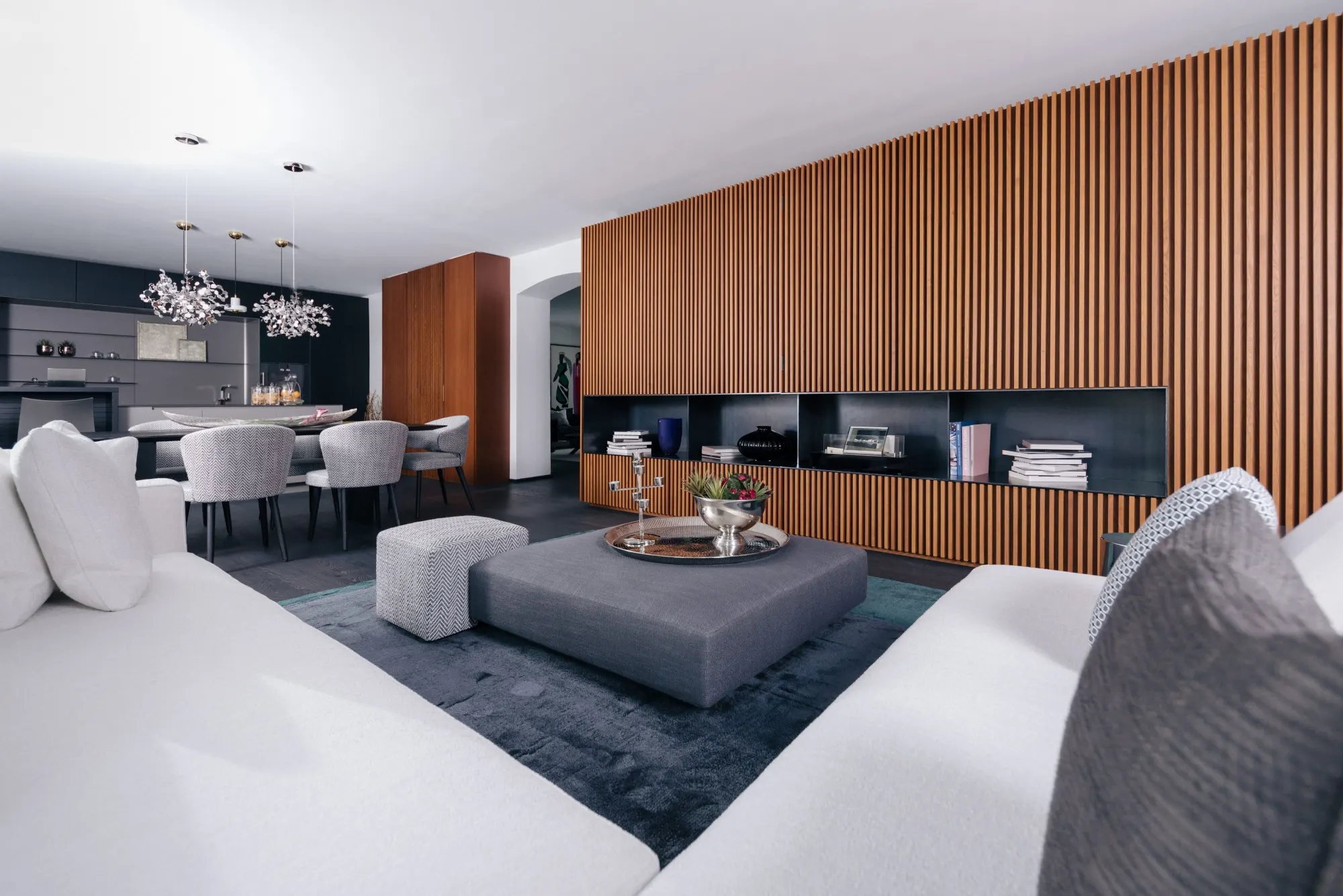 Wohnraum von FAMLER mit weißem Sofa, Holzlamellenwand und offenem Essbereich