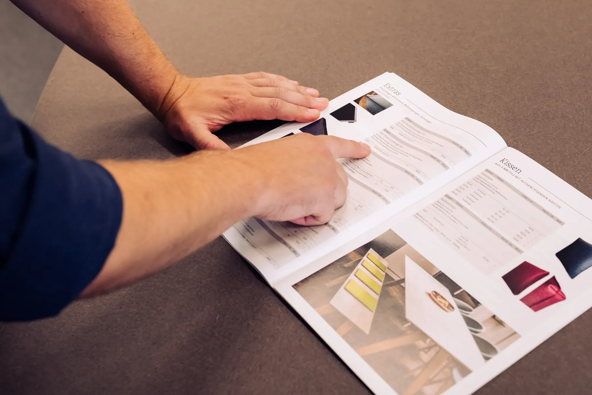 Hand blättert im Preisfolder von Filzwerk mit Farbmustern