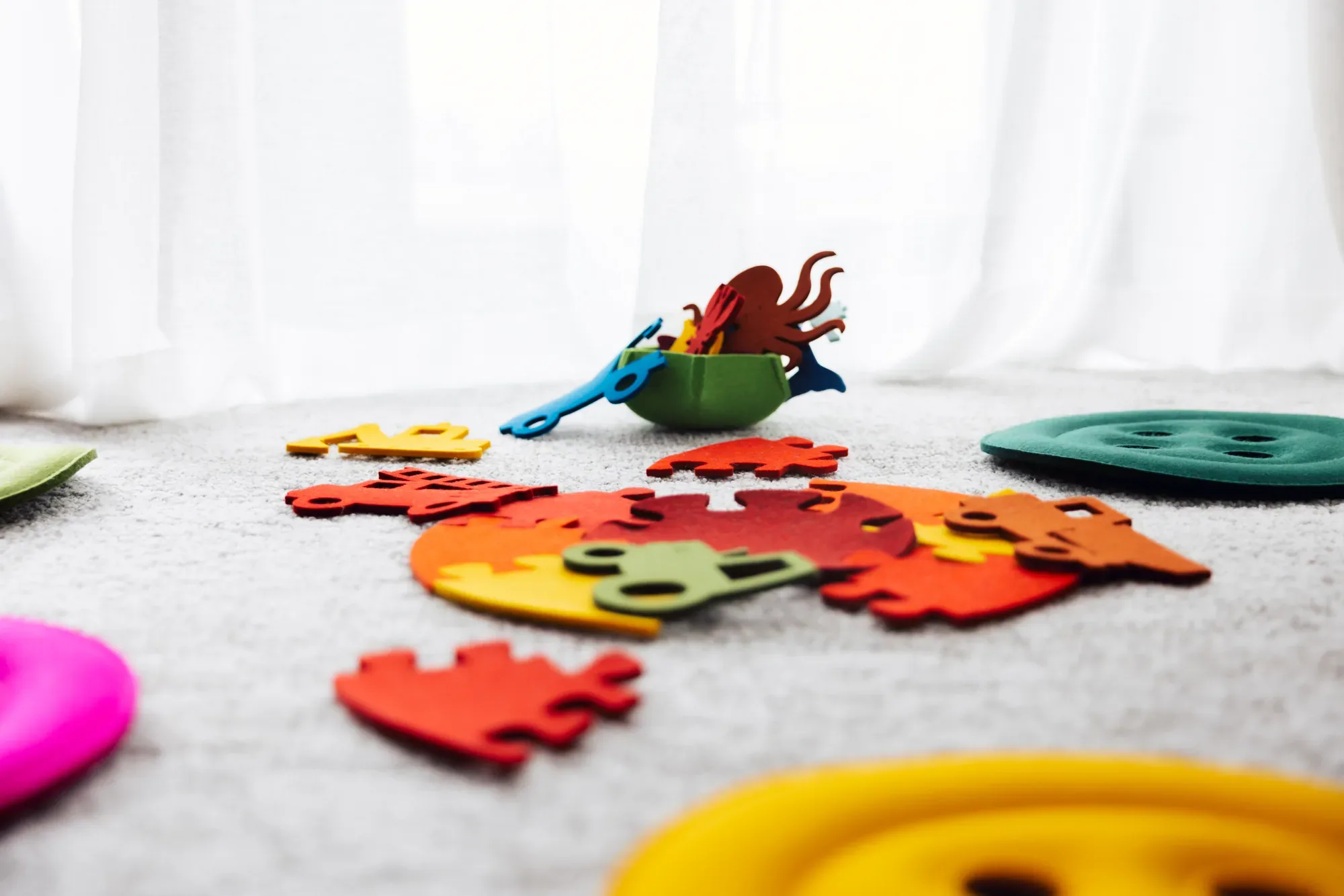 Bunte Filzpuzzles und Knopfkissen aus der Kinderkollektion auf einem Teppich