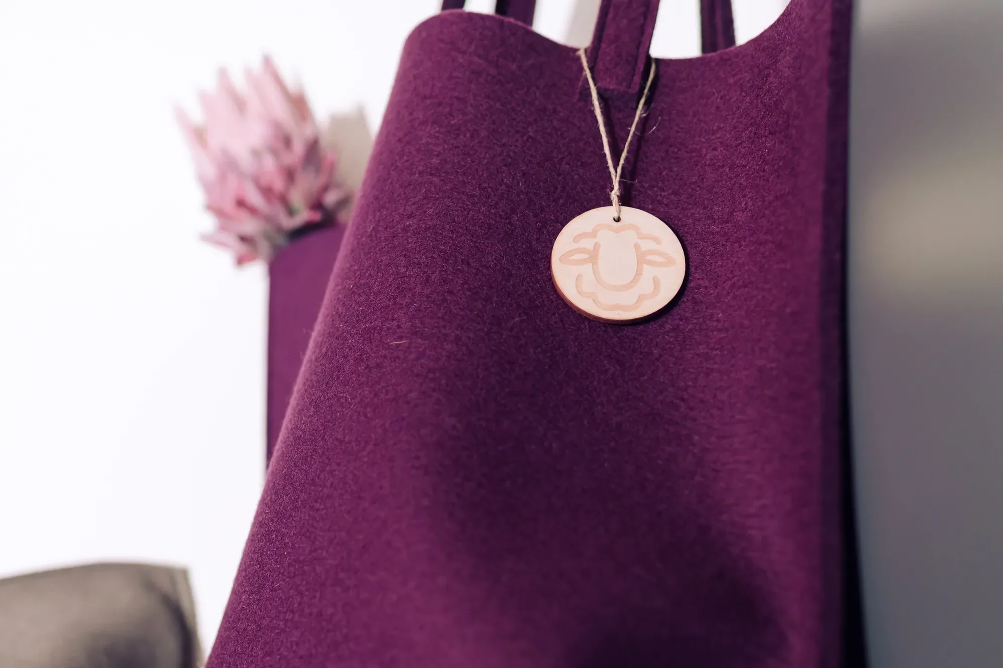 Violette Filztasche mit runder Lederplakette, in die der Schafkopf geprägt ist