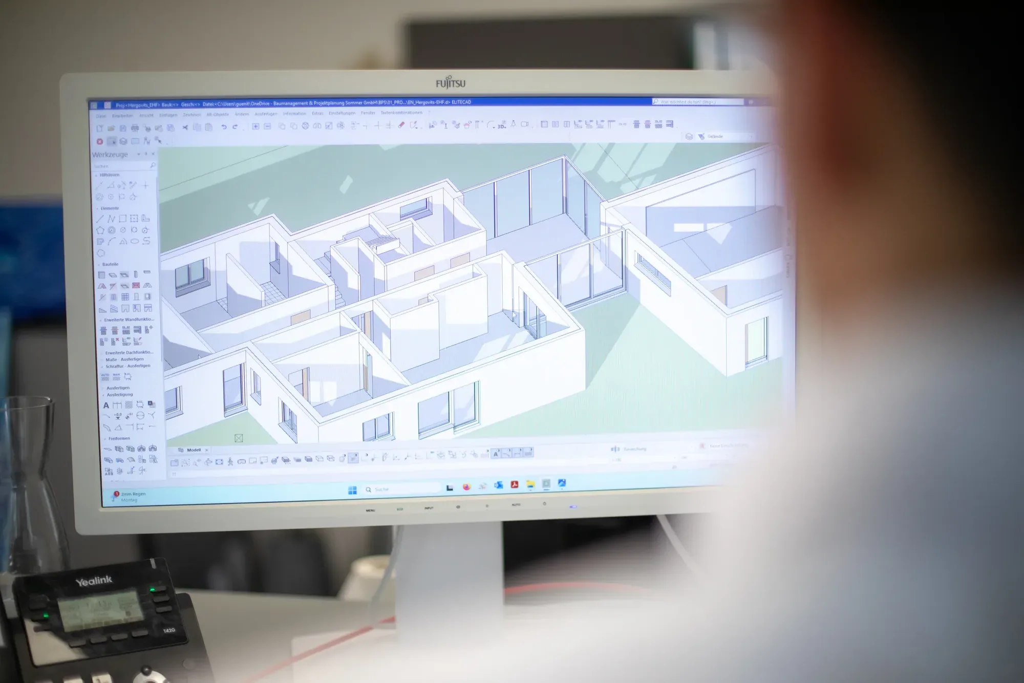 Arbeitsplatz mit Fujitsu-Monitor, auf dem ein 3D-Grundriss eines Mehrraum-Gebäudes in isometrischer Ansicht angezeigt wird
