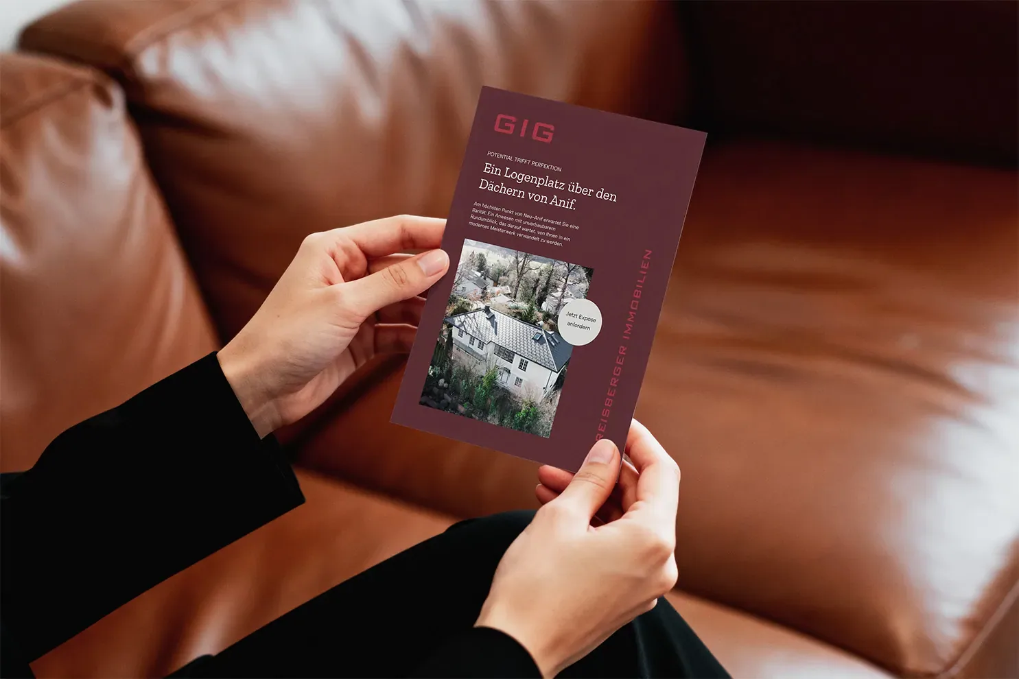 Flyer von GIG Greisberger Immobilien mit einem Objekt in Anif in der Hand