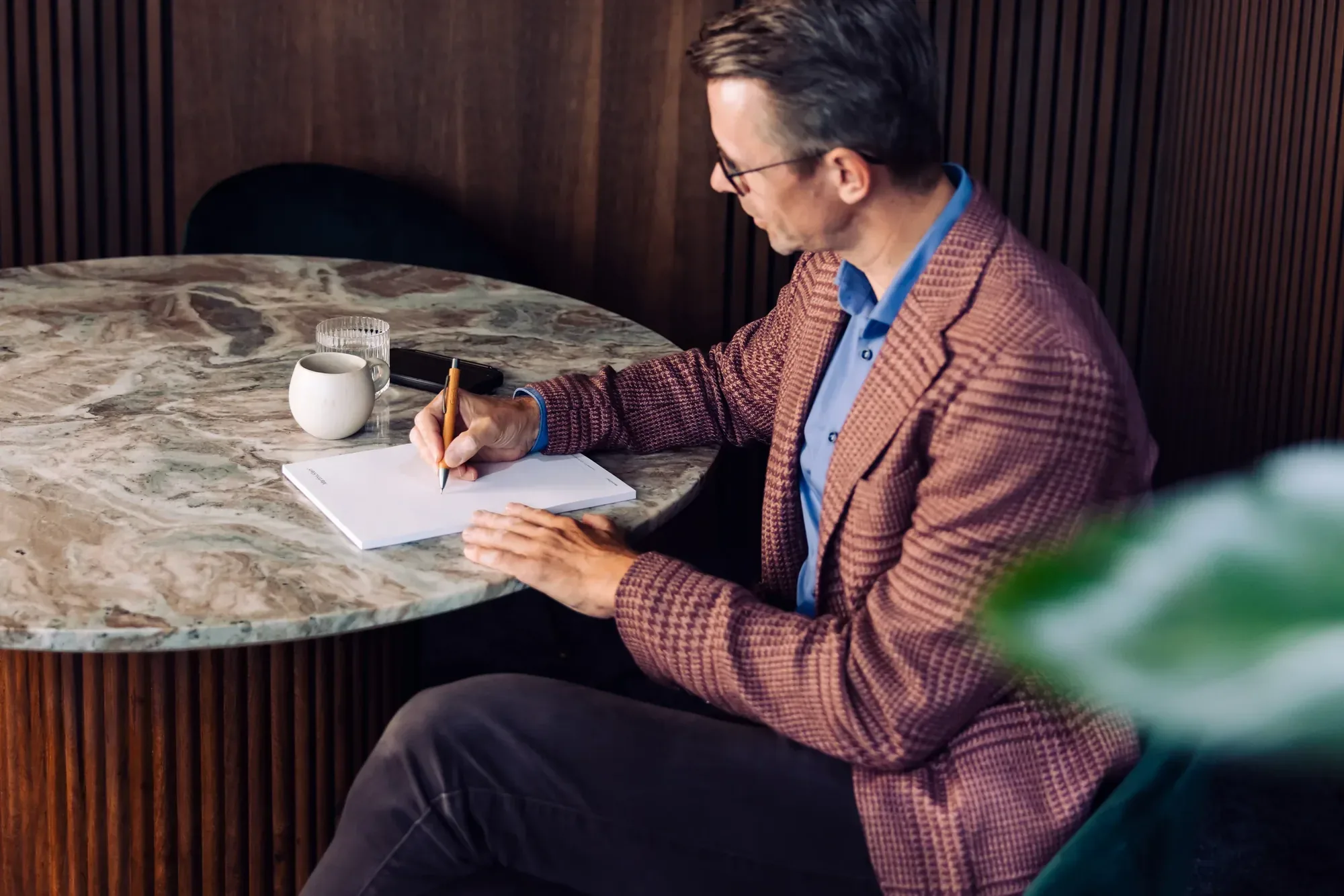 Peter Hauser macht sich an einem Marmortisch Notizen