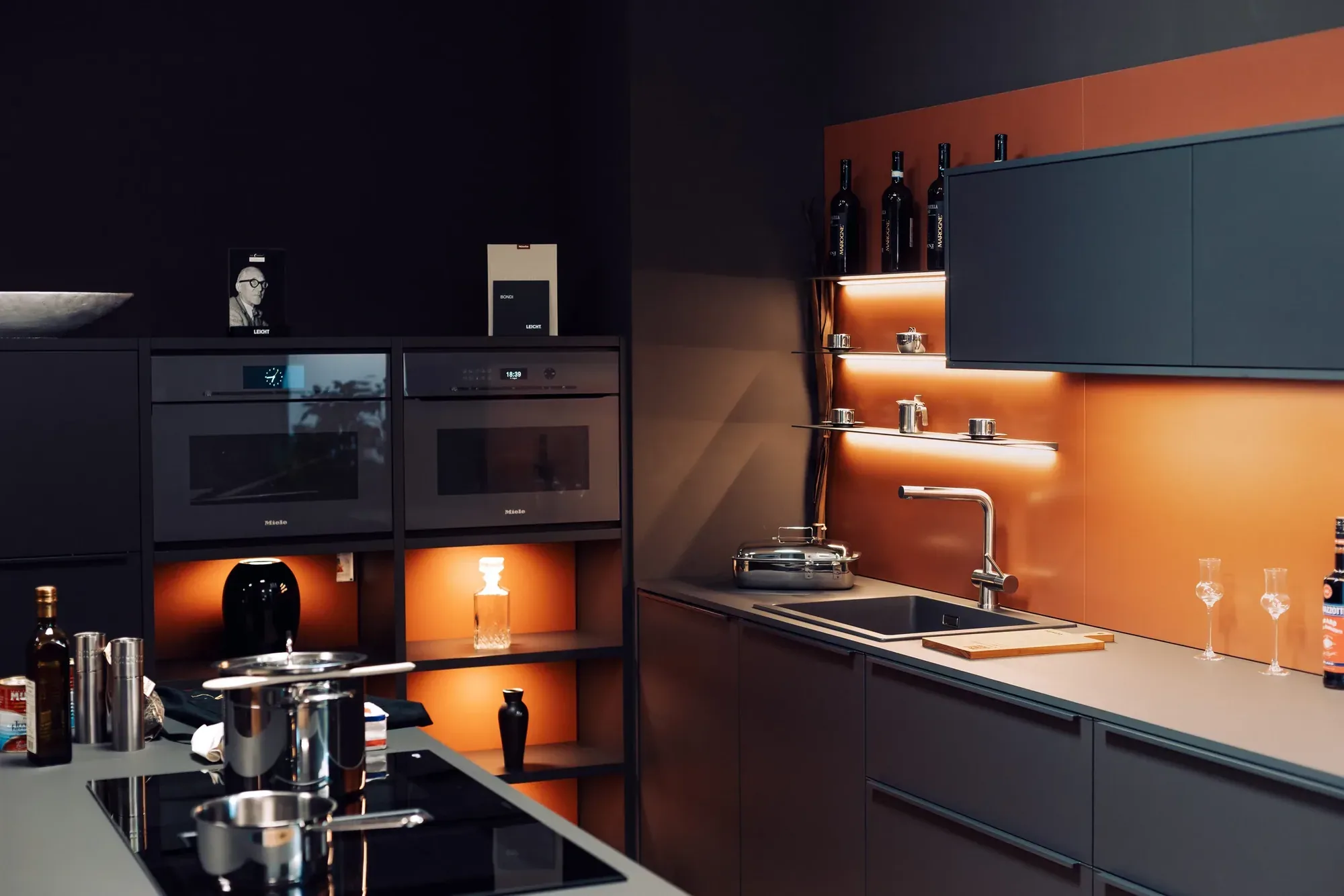 Dunkle Küche mit orangefarbener Rückwand und beleuchteten Nischen