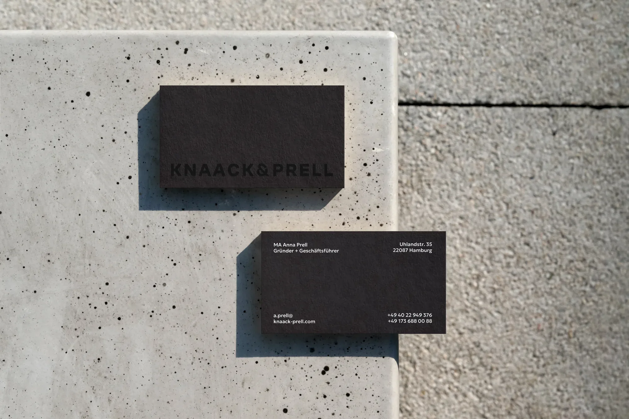 Schwarze Visitenkarten von Knaack & Prell auf Sichtbeton