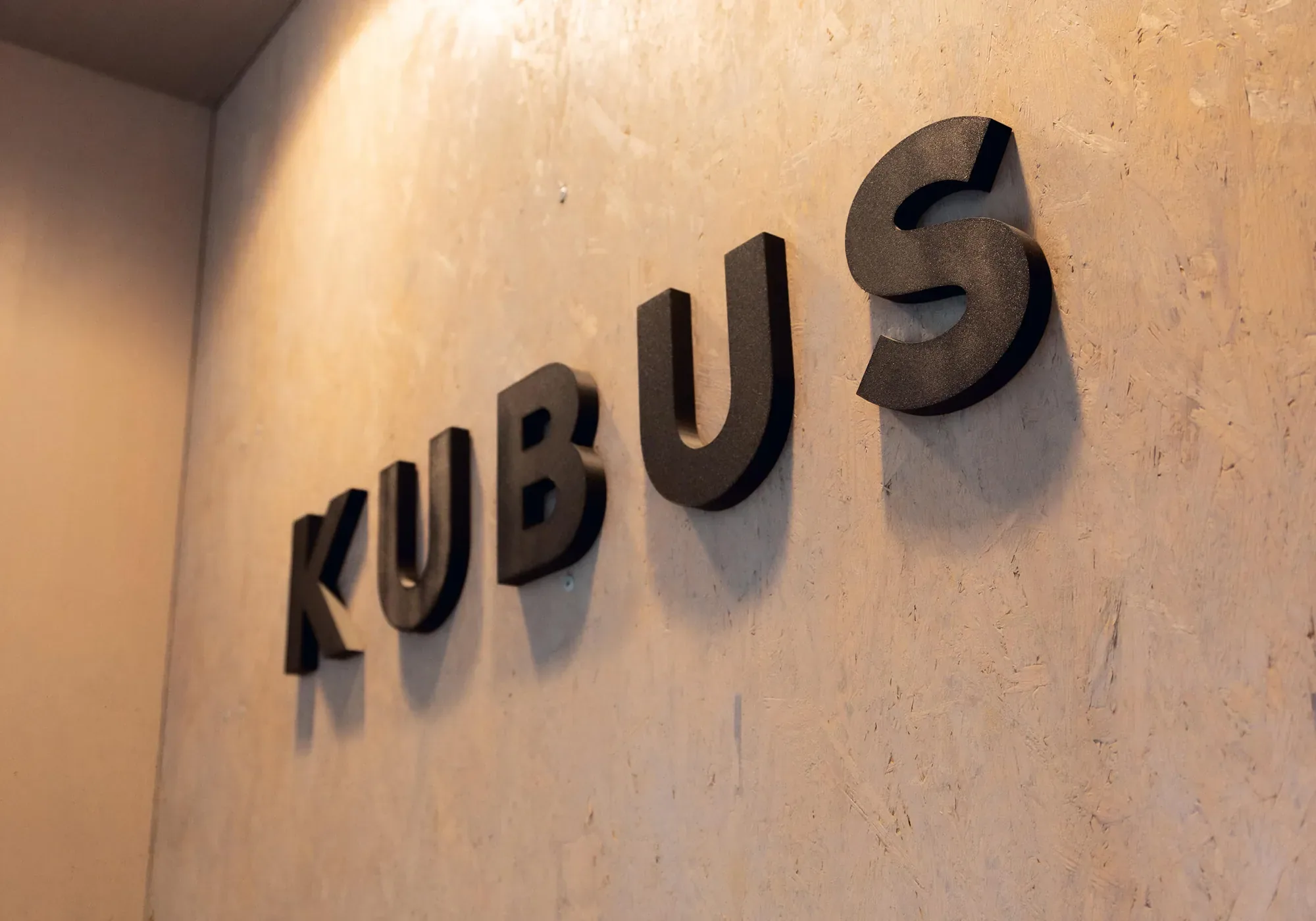 KUBUS-Schriftzug in dunklen Buchstaben an der Wand
