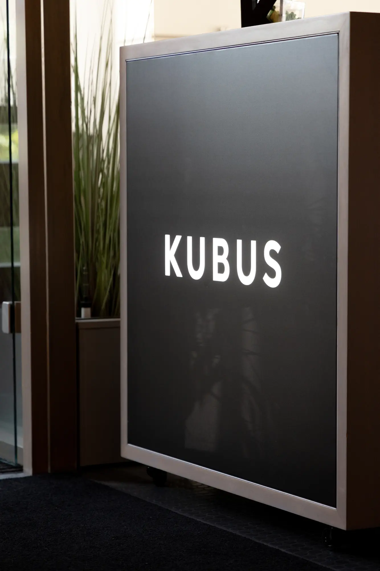 Schwarzes KUBUS-Schild am Eingang des Büros