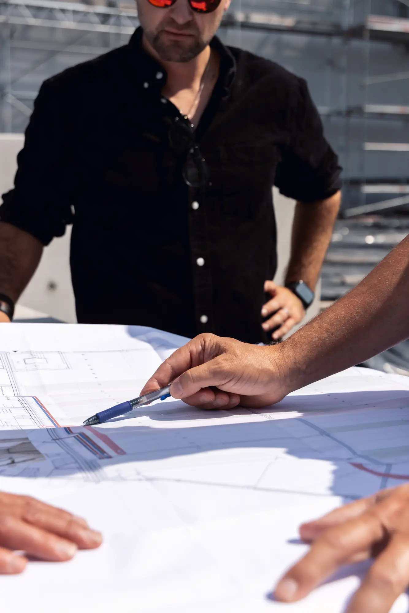 Bauleiter zeigt auf der Baustelle mit dem Stift auf einen Plan