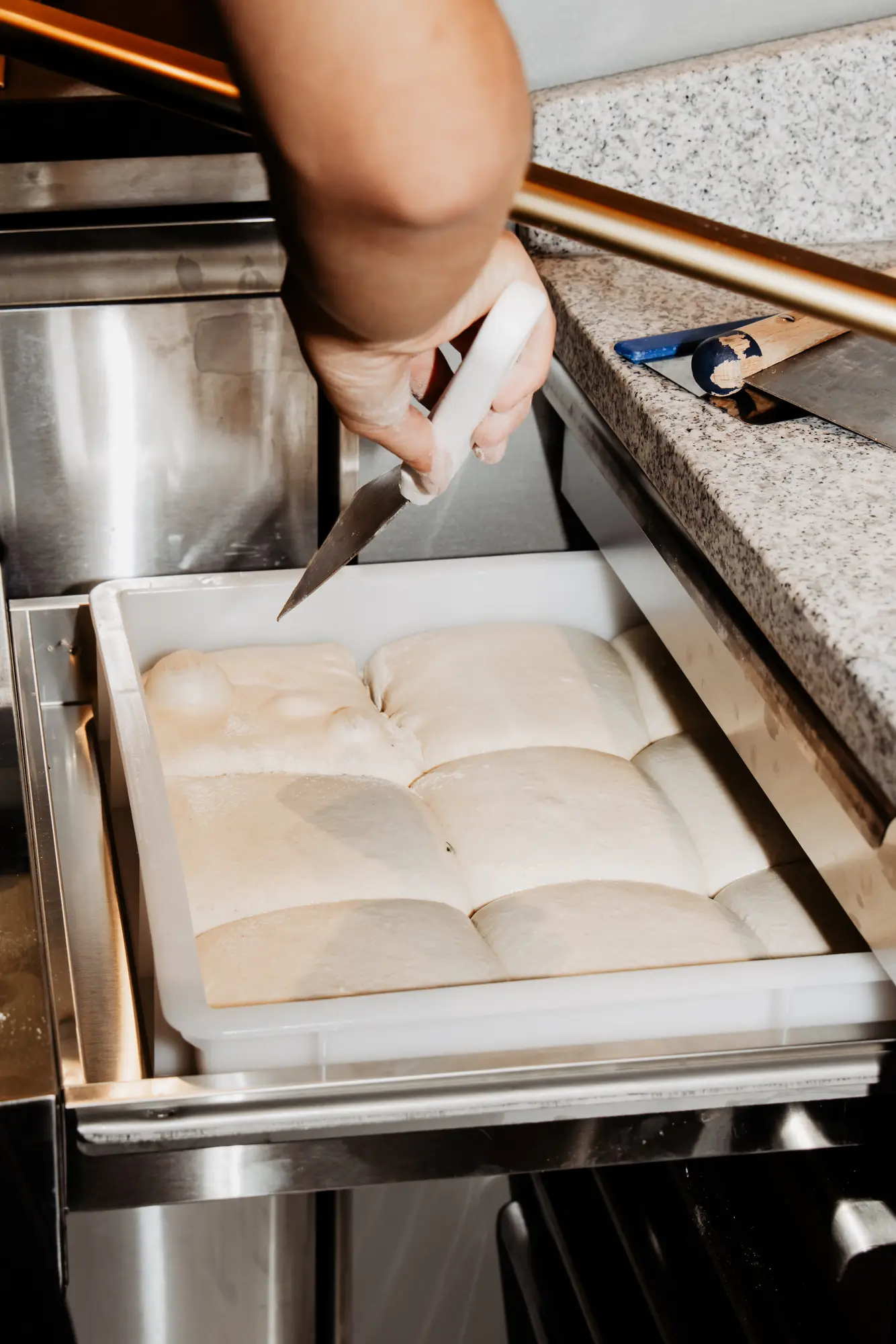 Teiglinge in einer Gärbox werden mit dem Spachtel portioniert