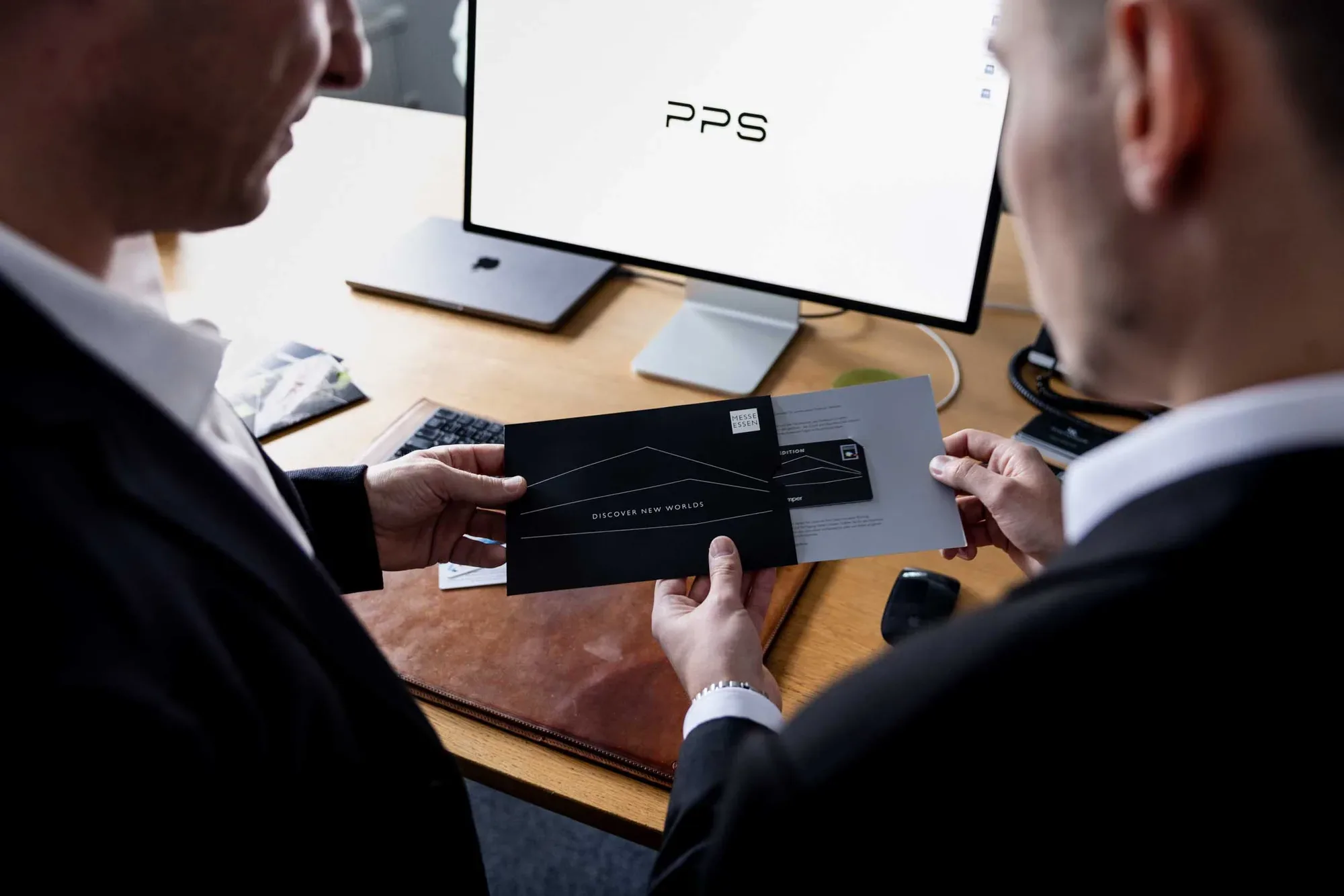 Zwei Männer prüfen eine schwarze Karte am Schreibtisch