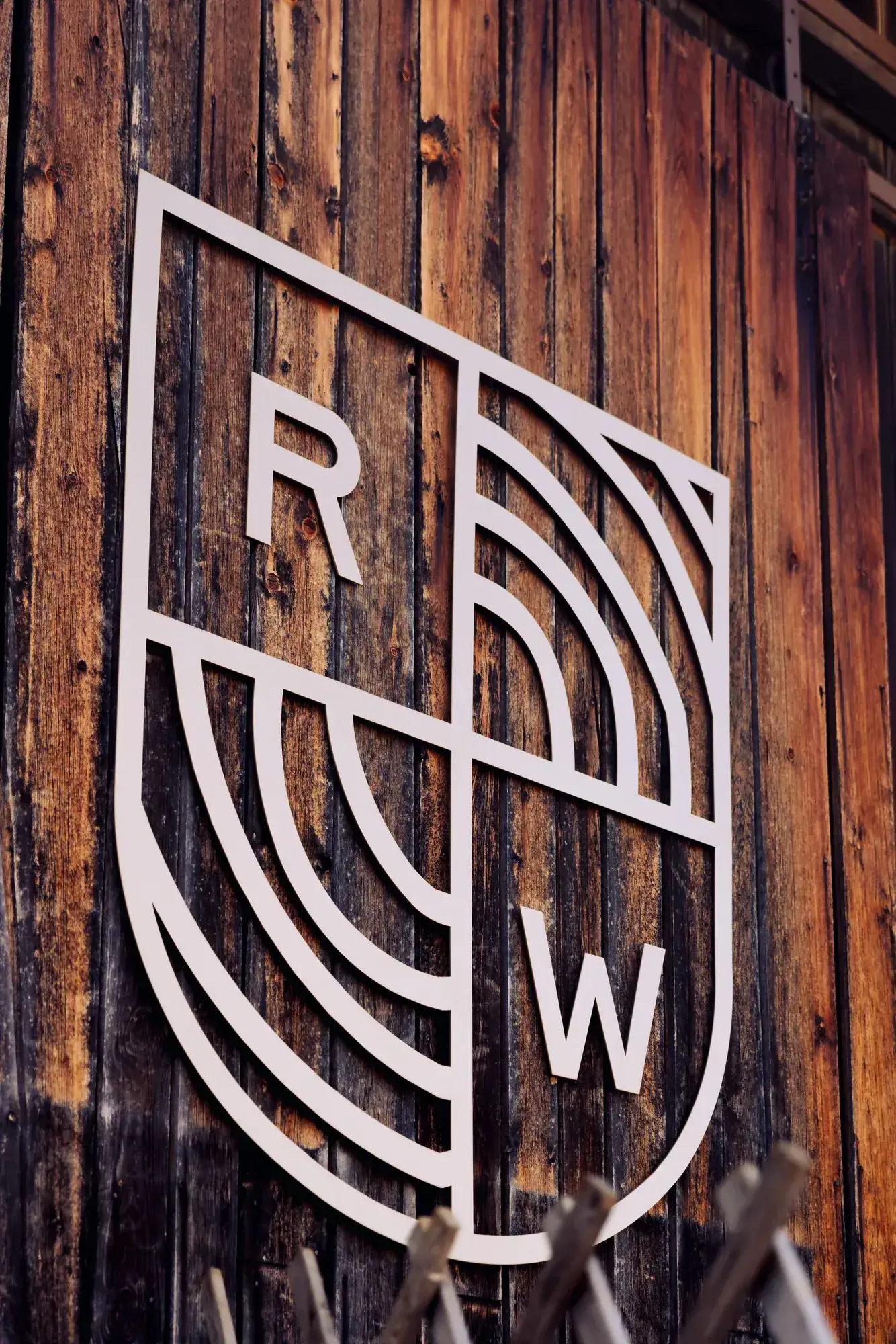 Das Raumkunst-Wappen als Schild an der Holzfassade