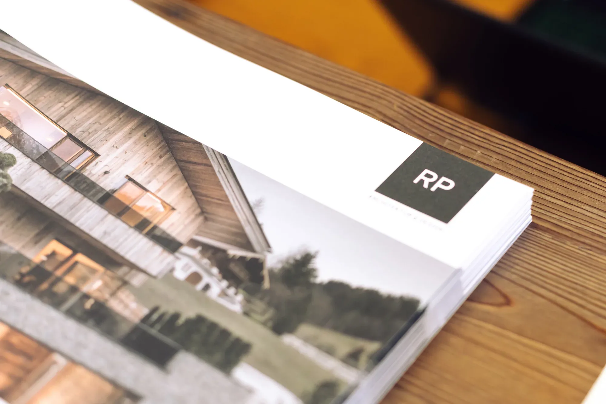 Broschüre von RP Architektur mit Projektfoto auf einem Holztisch