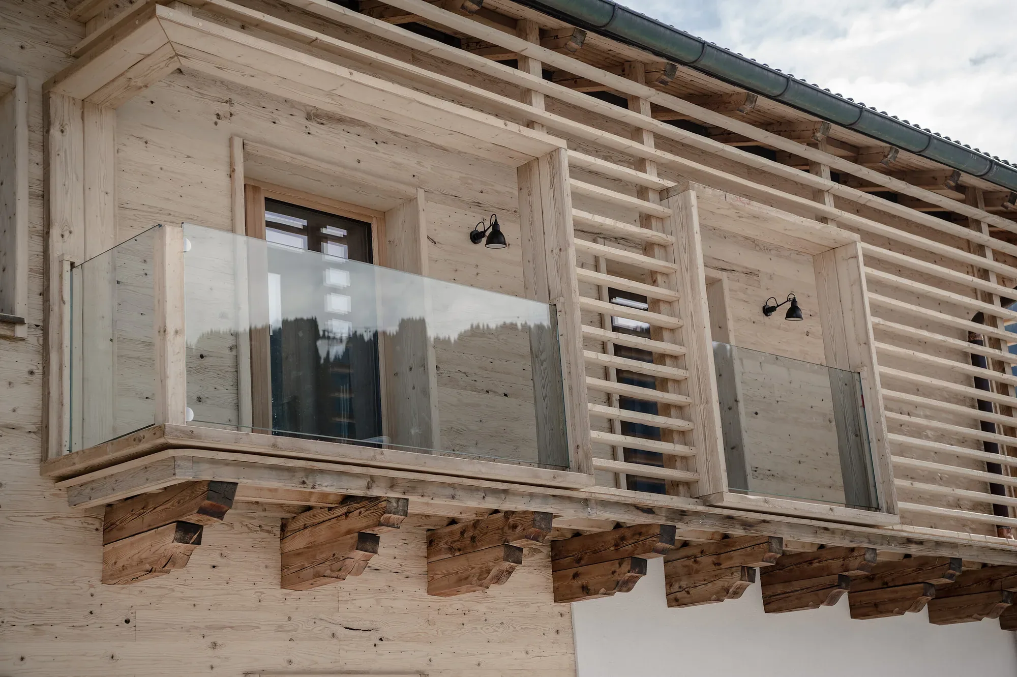 Holzfassade eines Chalets mit Lattung und Glasbalkon