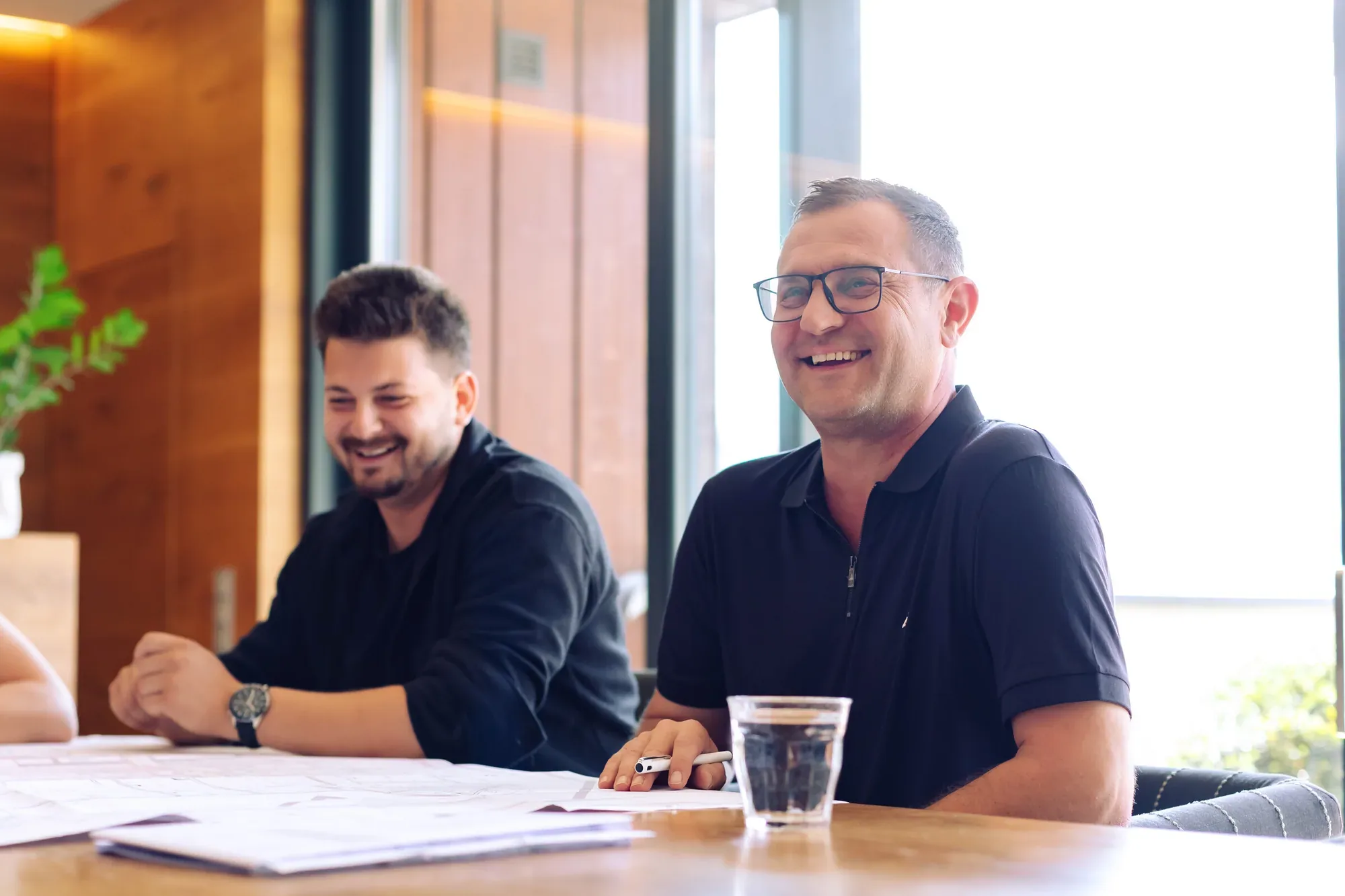 Wolfgang Rohrmoser lacht mit einem Kollegen am Besprechungstisch