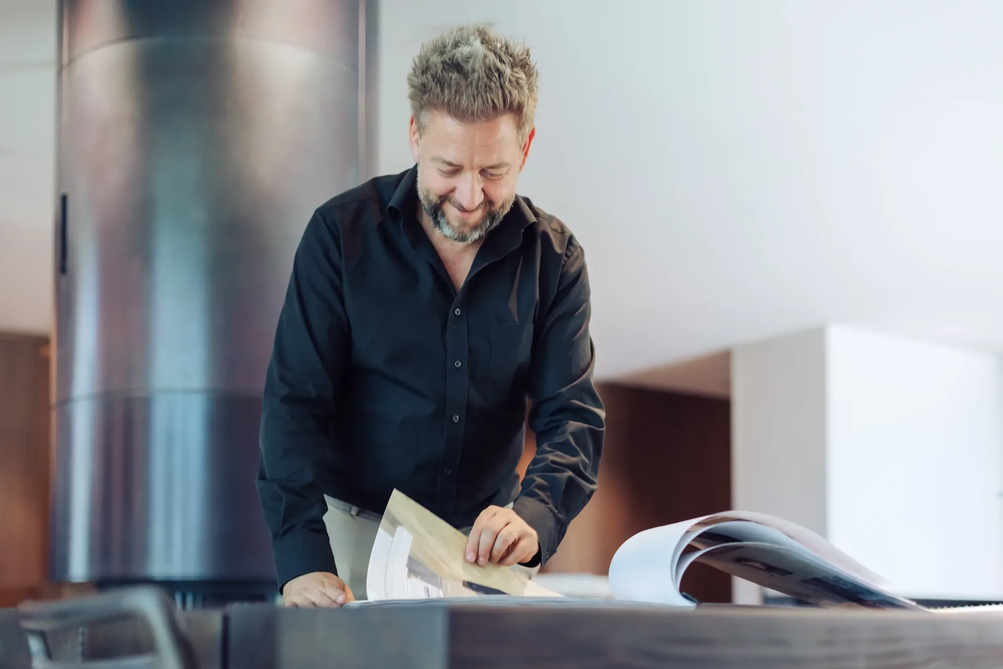 Stefan Schinharl blättert im Showroom in Projektmappen und Magazinen