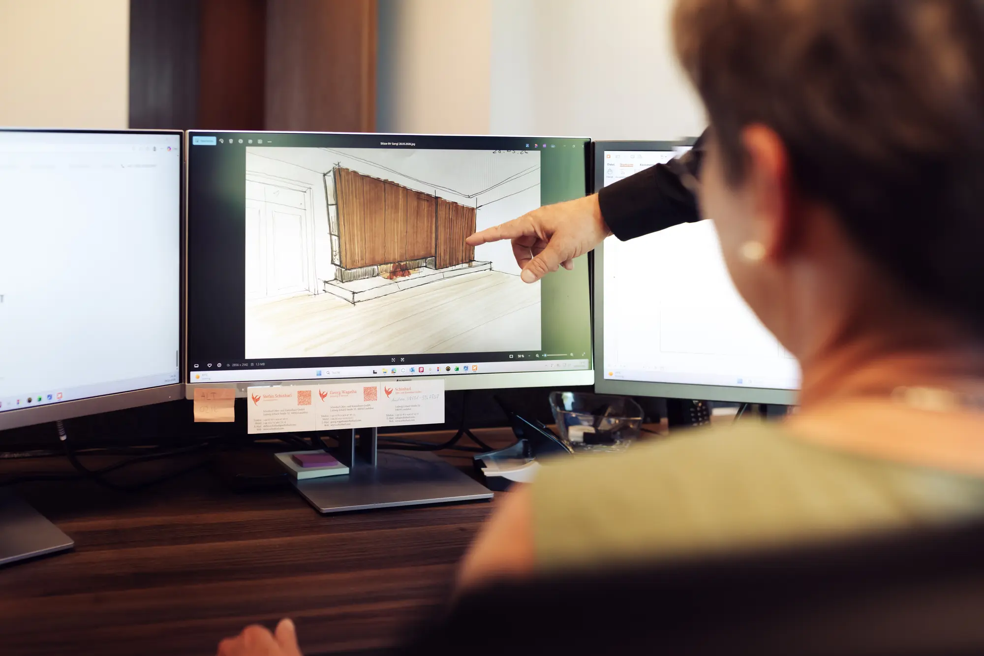 Planerin zeigt am Bildschirm den 3D-Entwurf einer Kaminwand