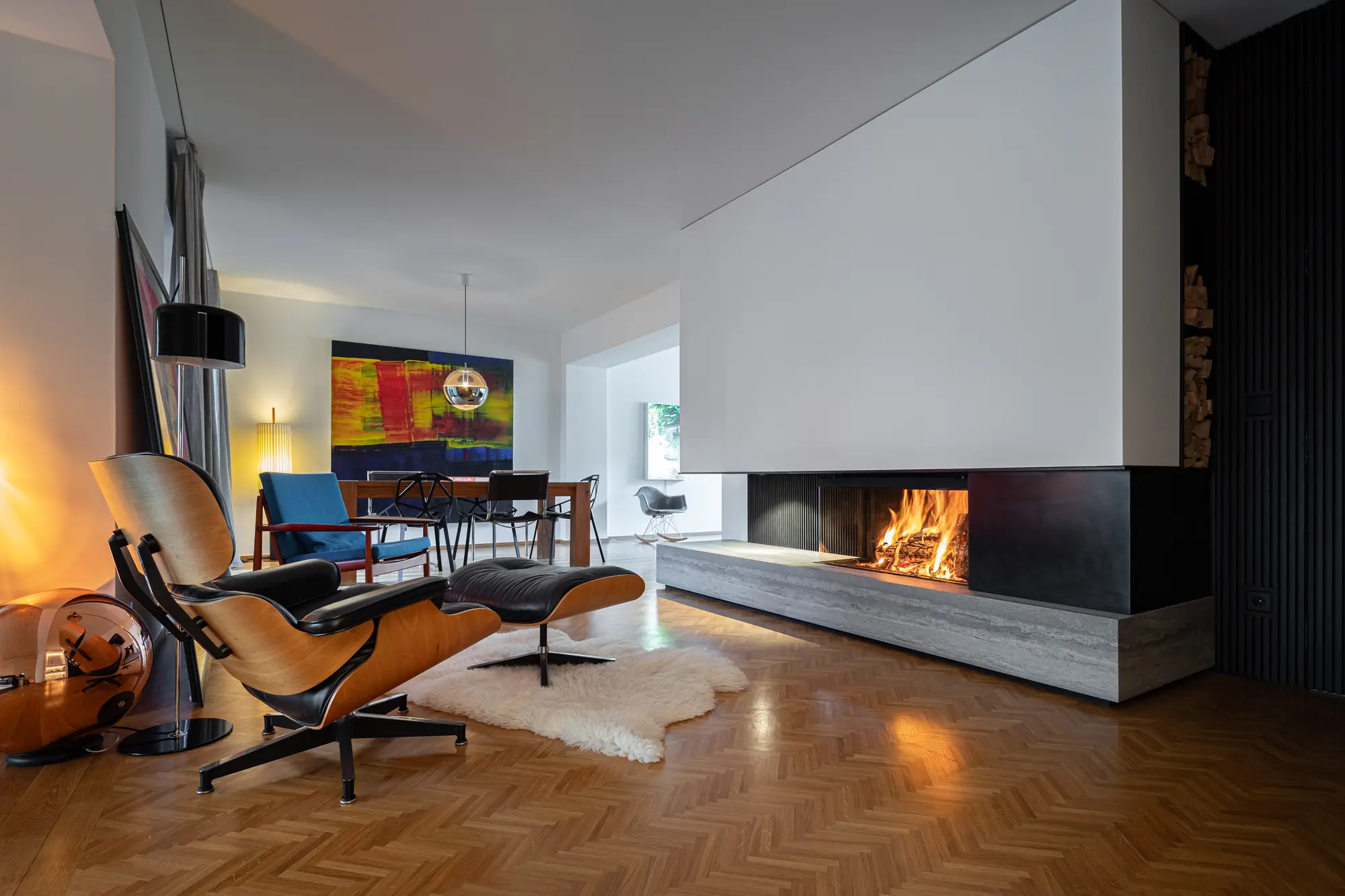 Weißer Eckkamin mit Holzfeuer in einem Wohnzimmer mit Fischgrätparkett