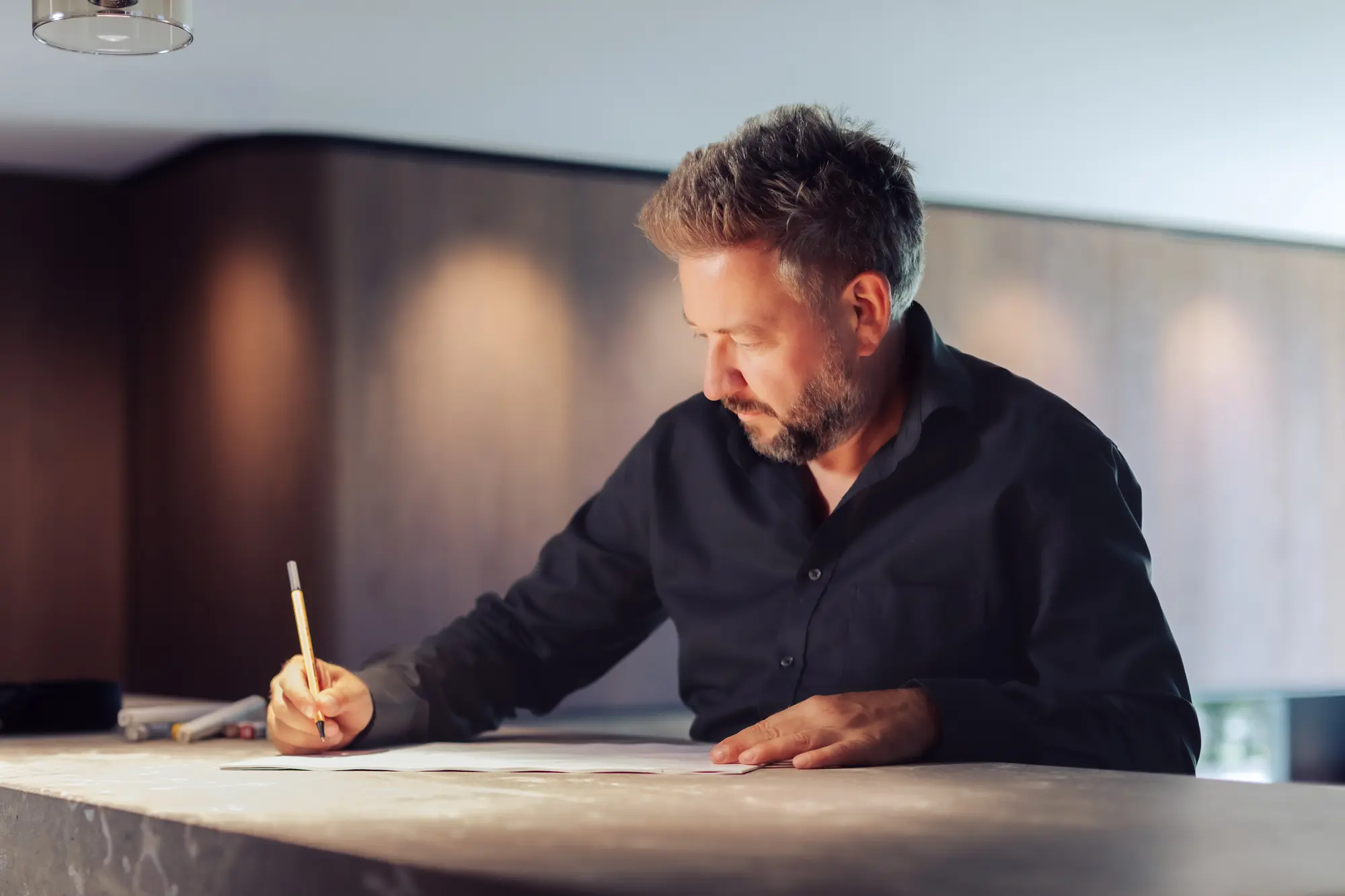 Stefan Schinharl zeichnet an einem Steintisch im Showroom
