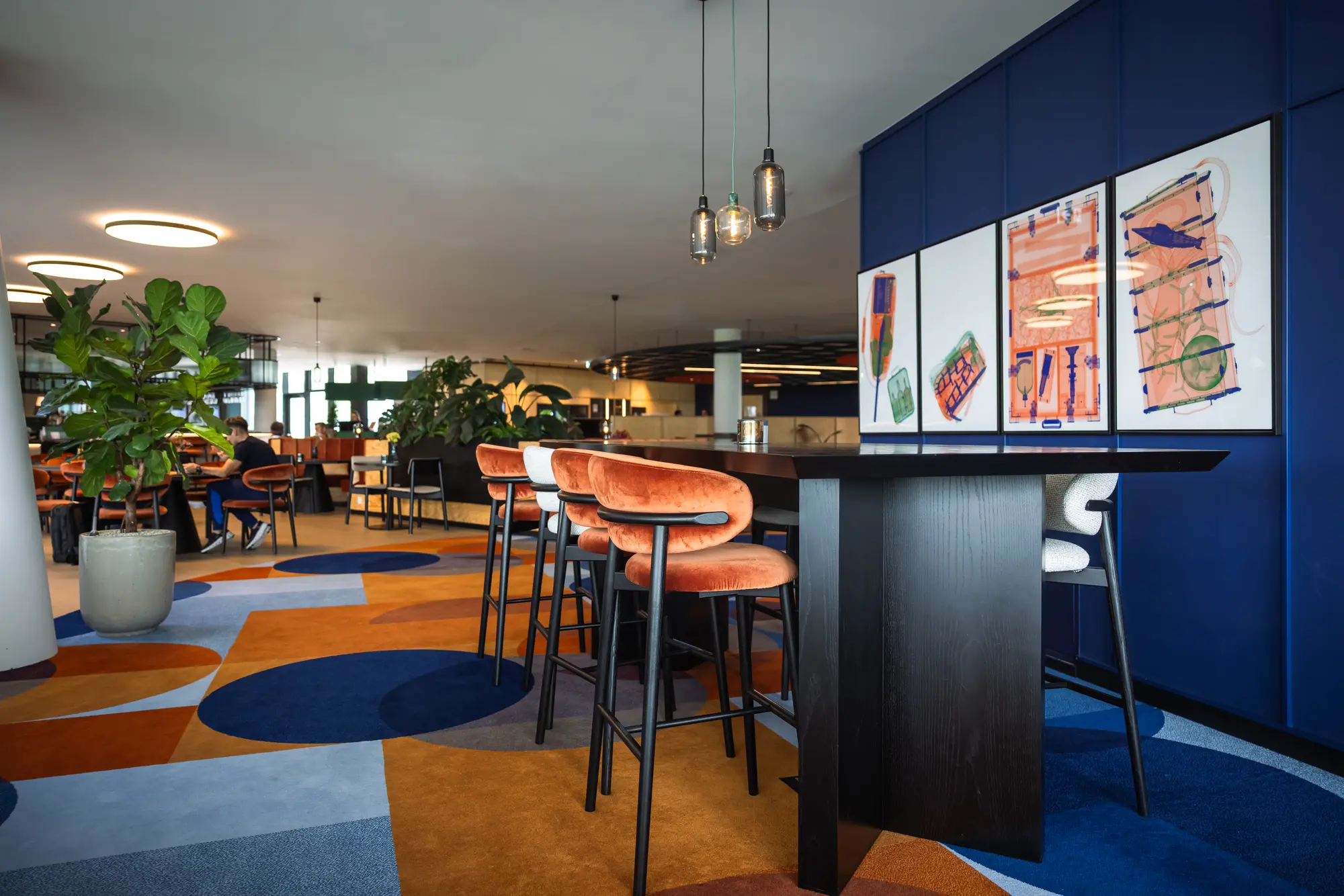 Lounge mit Hochtischen, orangen Barhockern und blauer Wand im The Passenger