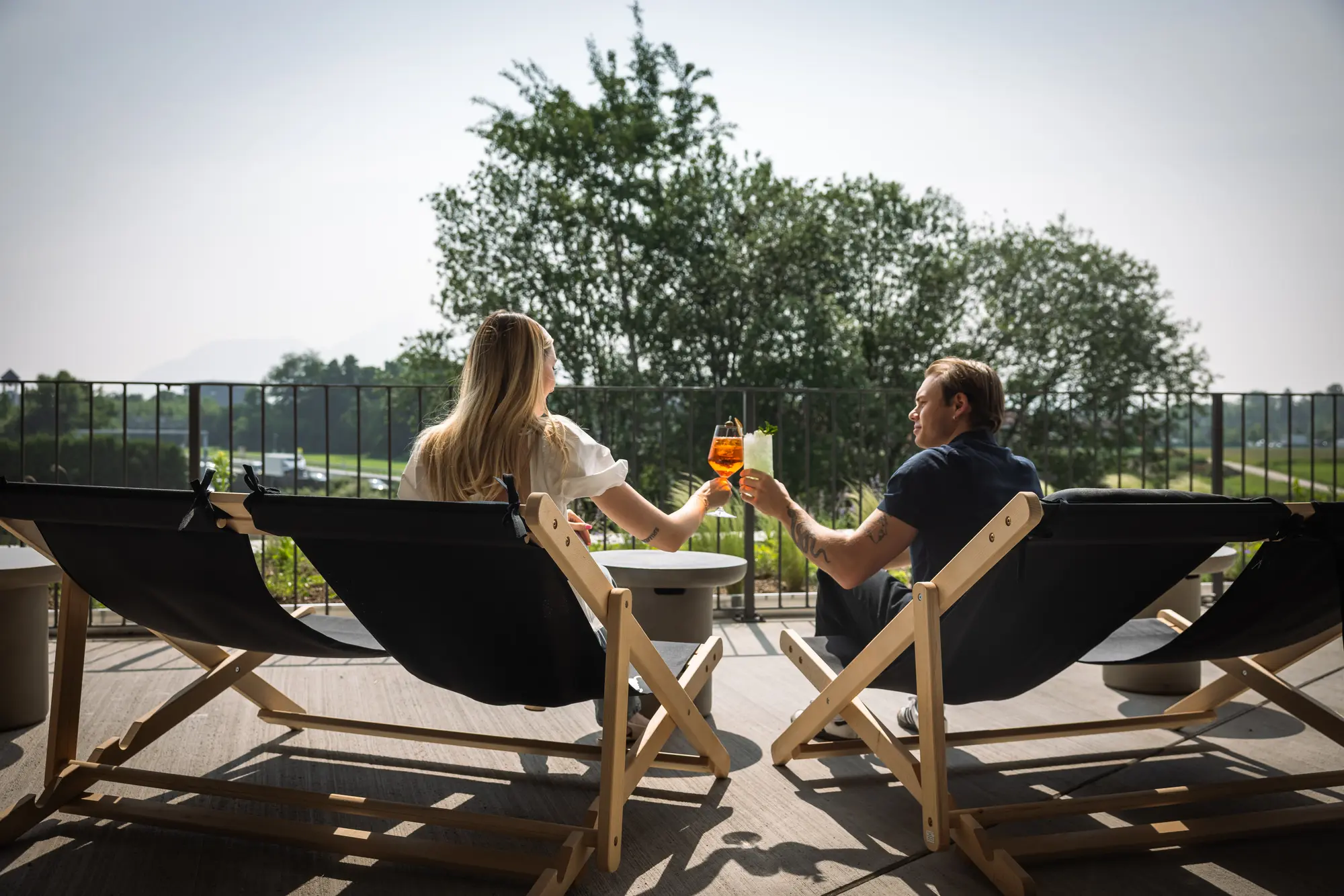 Zwei Gäste in Liegestühlen auf der Hotelterrasse mit Aperitif