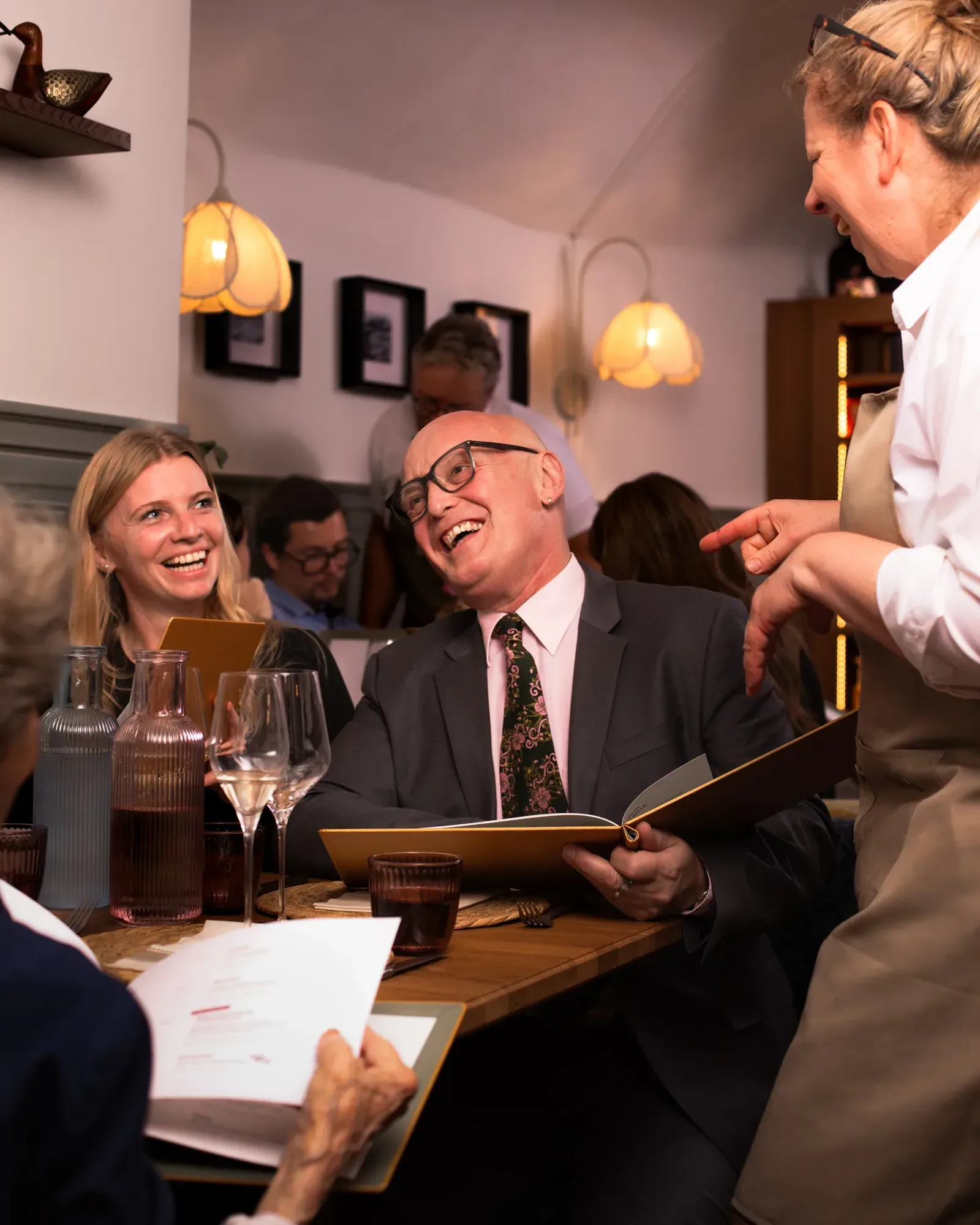 Gäste lachen bei der Bestellung mit einer Kellnerin im Restaurant Zia Mizzi
