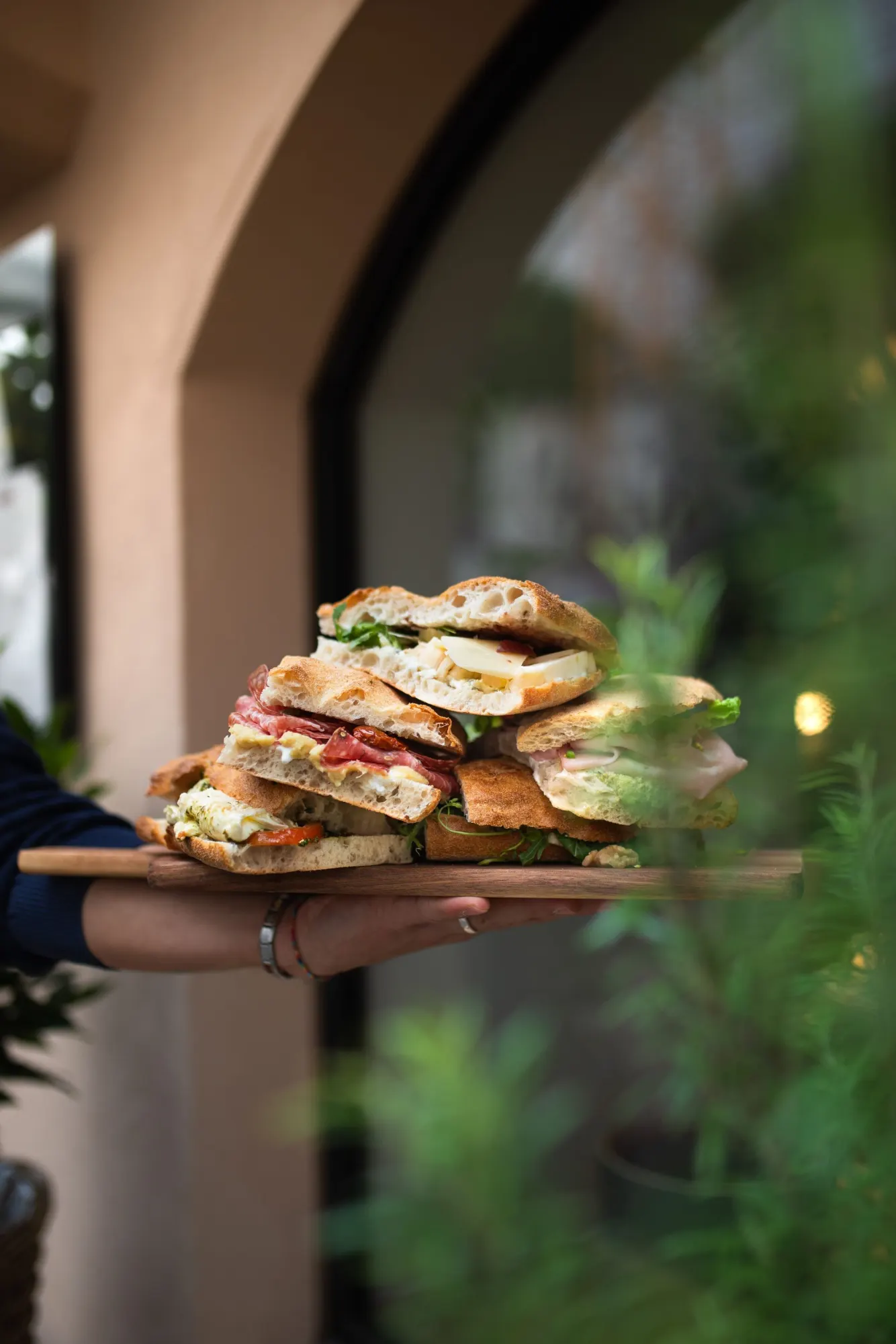 Holzbrett mit belegten Panini, gehalten vor dem Eingang von Zia Mizzi