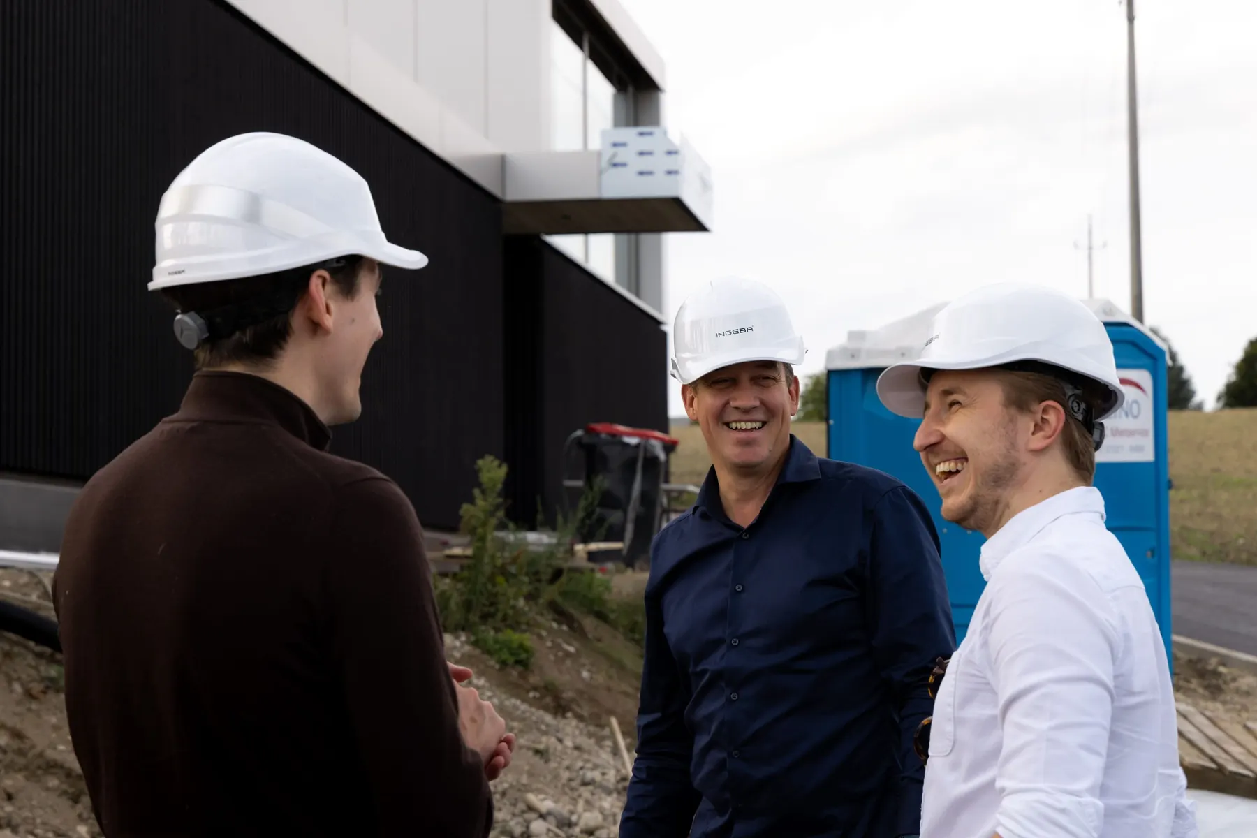 Gespräch mit einem Kunden von Ingeba auf der Baustelle, alle tragen weiße Bauhelme