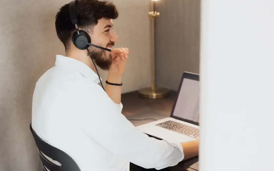 Vertriebsmitarbeiter mit Headset führt am Laptop ein Verkaufsgespräch