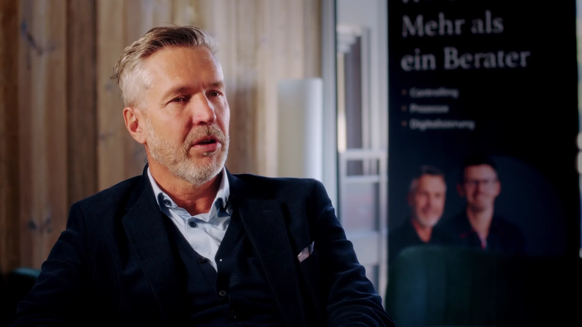 Einer der beiden Inhaber von HWXB im Videointerview vor einem Roll-up mit der Aufschrift Mehr als ein Berater
