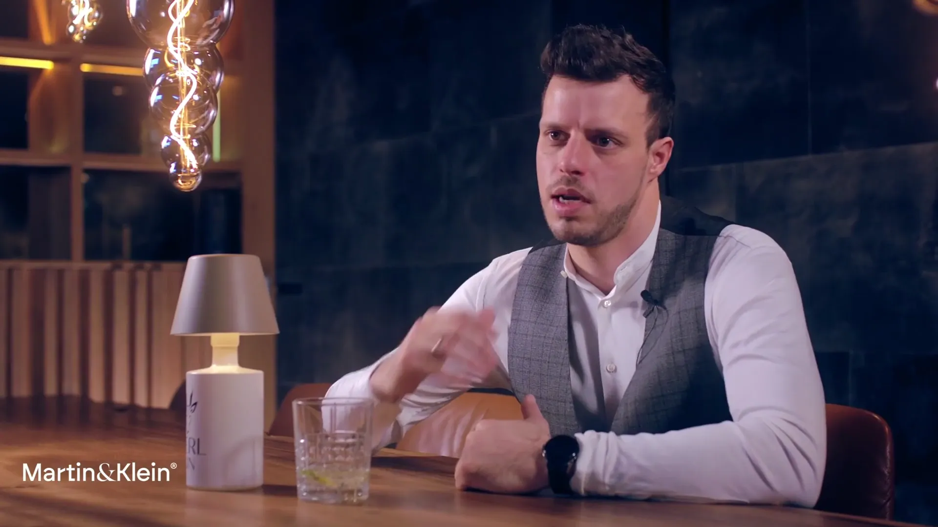 Simon Siller, Geschäftsführer von KURZZEiTmiete, im Videointerview an einem Tisch mit Tischleuchte