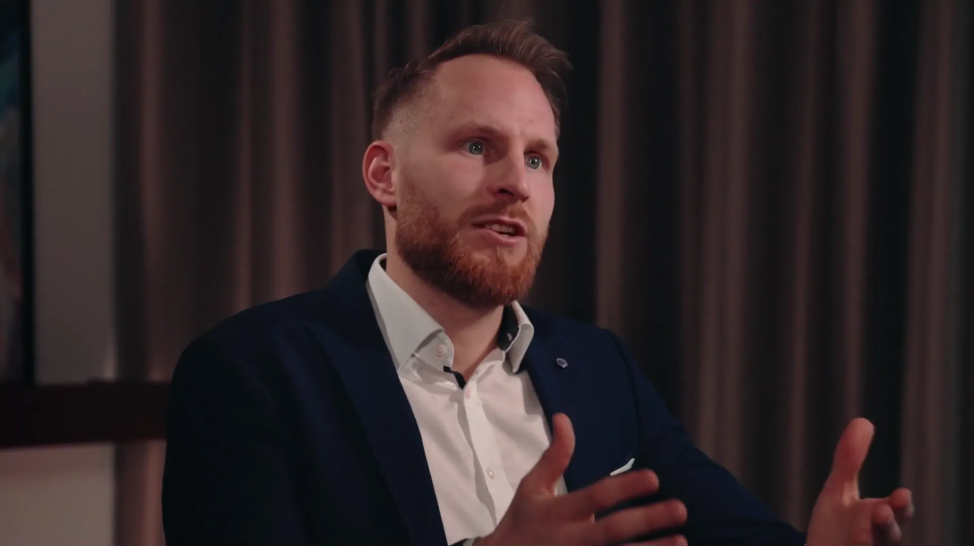 Lukas Rother, Gründer von Rother Consulting, erzählt im Videointerview vor einem dunklen Vorhang