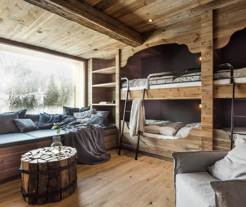 Chaletzimmer mit Holzdecke, eingebauten Stockbetten und Fensterfront ins Tal