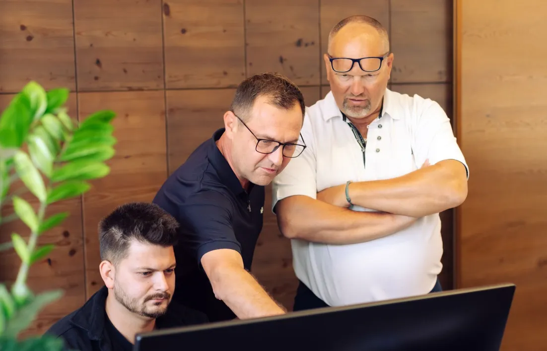 Drei Mitarbeiter schauen gemeinsam auf einen Bildschirm im Büro