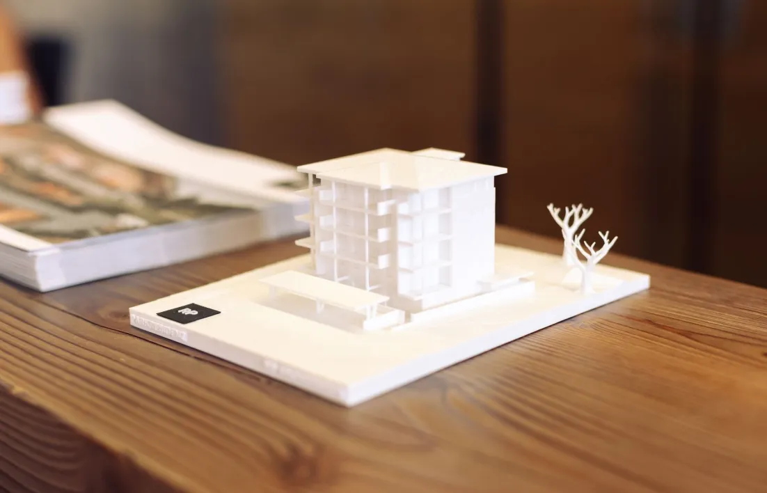 Weißes Architekturmodell eines Wohnhauses auf einem Holztisch