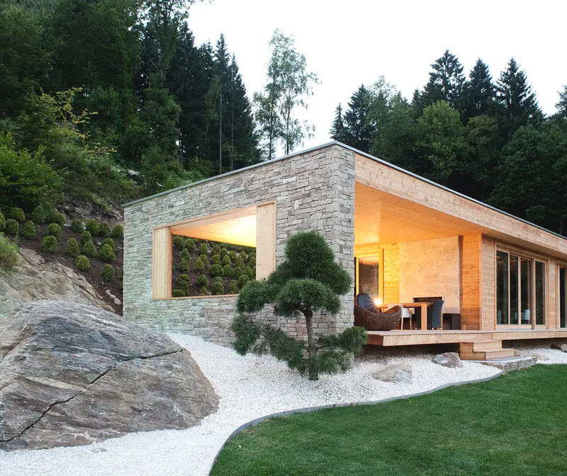 EFH Millstätter See — Natursteinhaus mit überdachter Holzterrasse am Hang