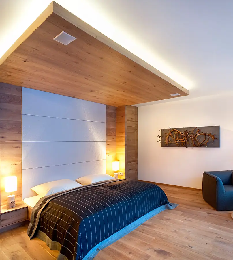 Schlafzimmer mit Holzbaldachin, indirekter Beleuchtung und gepolsterter Kopfwand