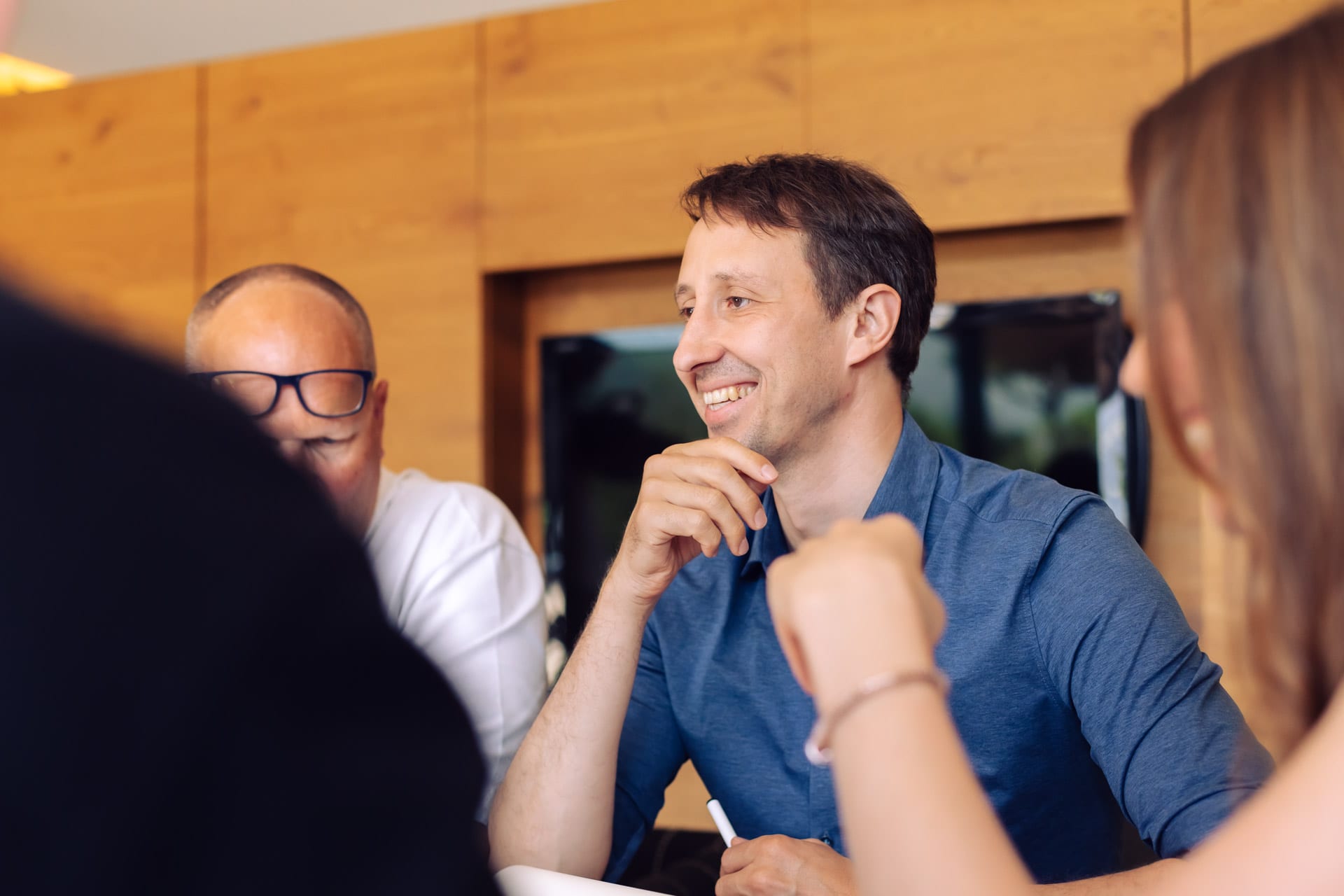 Drei Mitarbeitende im Gespräch am Besprechungstisch im Büro
